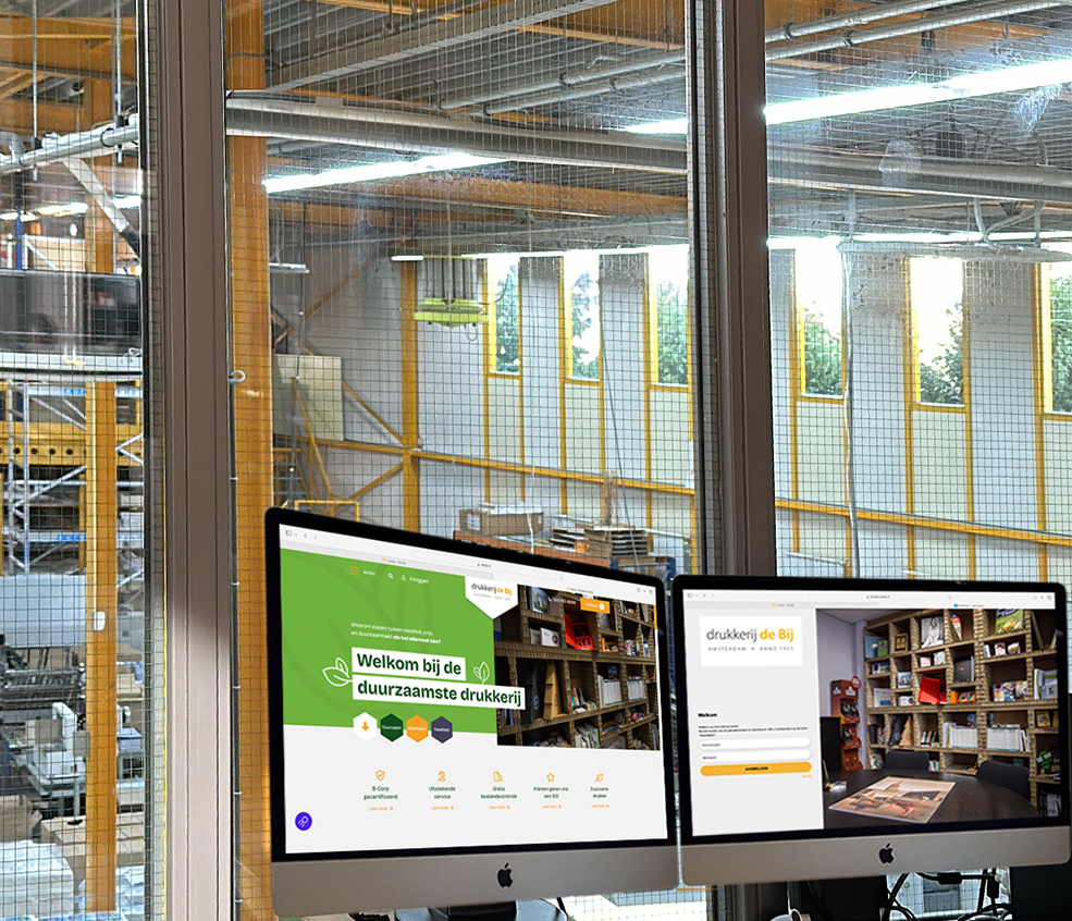 Drukkerij kantoor met computerschermen en raamzicht.