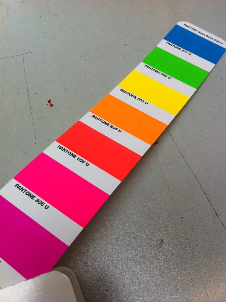 Kleurenwaaier met Pantone neonkleuren op grijze ondergrond.